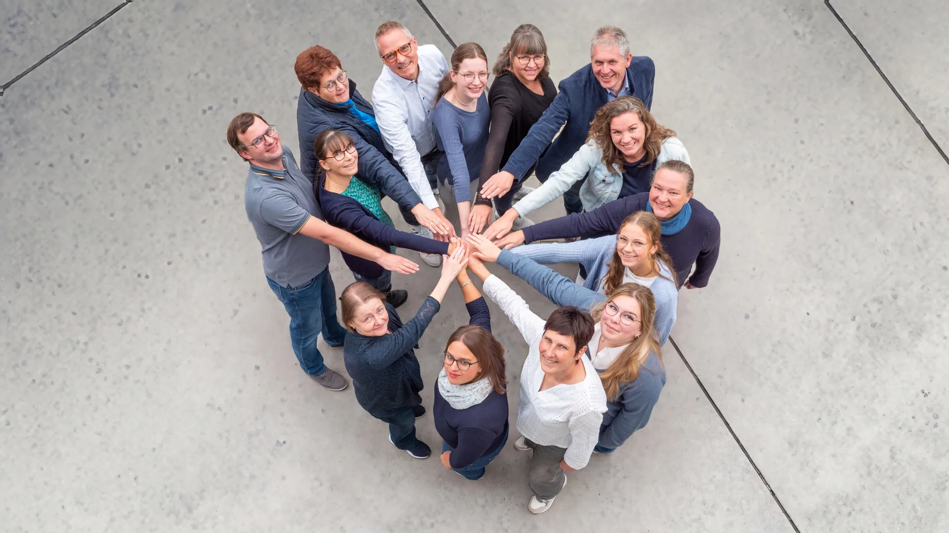 Das Team von Schmid und Hackl von oben im Kreis, alle legen die Hände in der Mitte zusammen